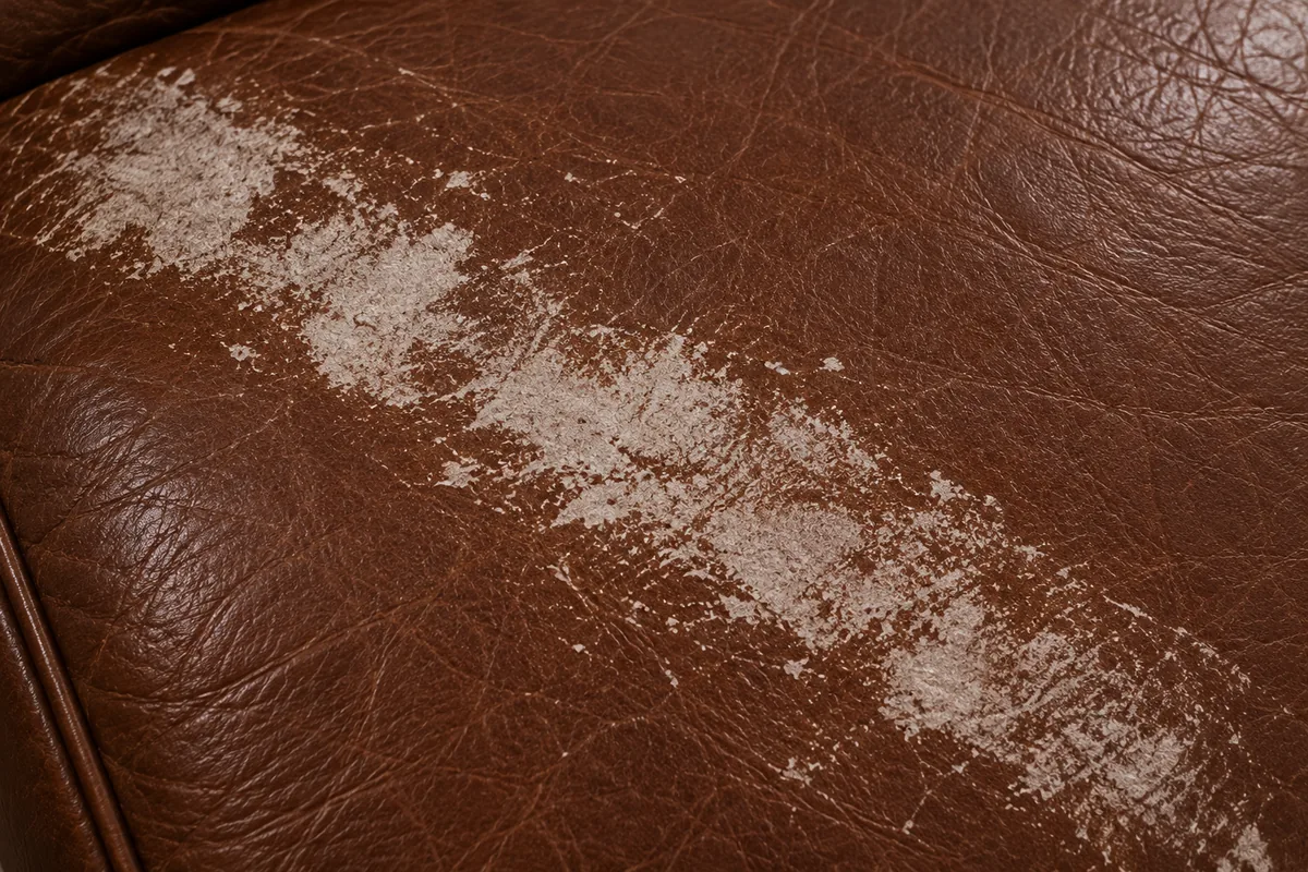 A broad diffuse pale patch on brown leather where the grain itself has been roughened open