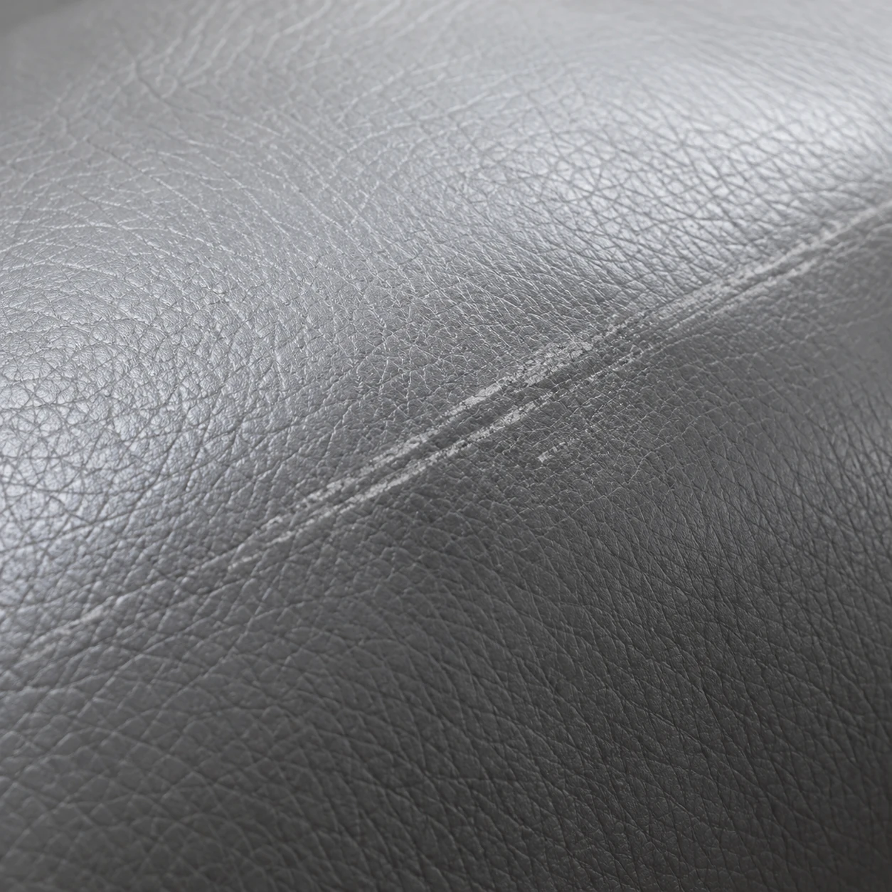 A long scuff rubbed dull into a grey leather panel