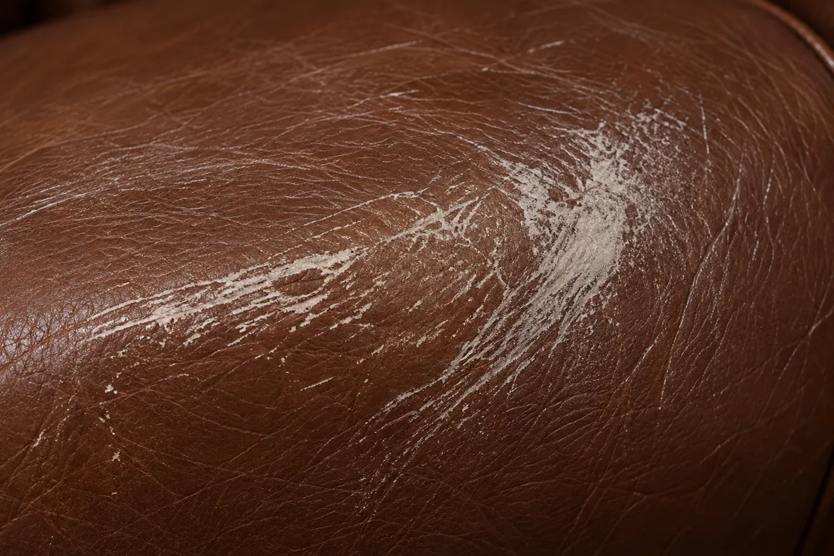 A close view of brown leather with a broad pale scuff smeared across the grain, its edges soft