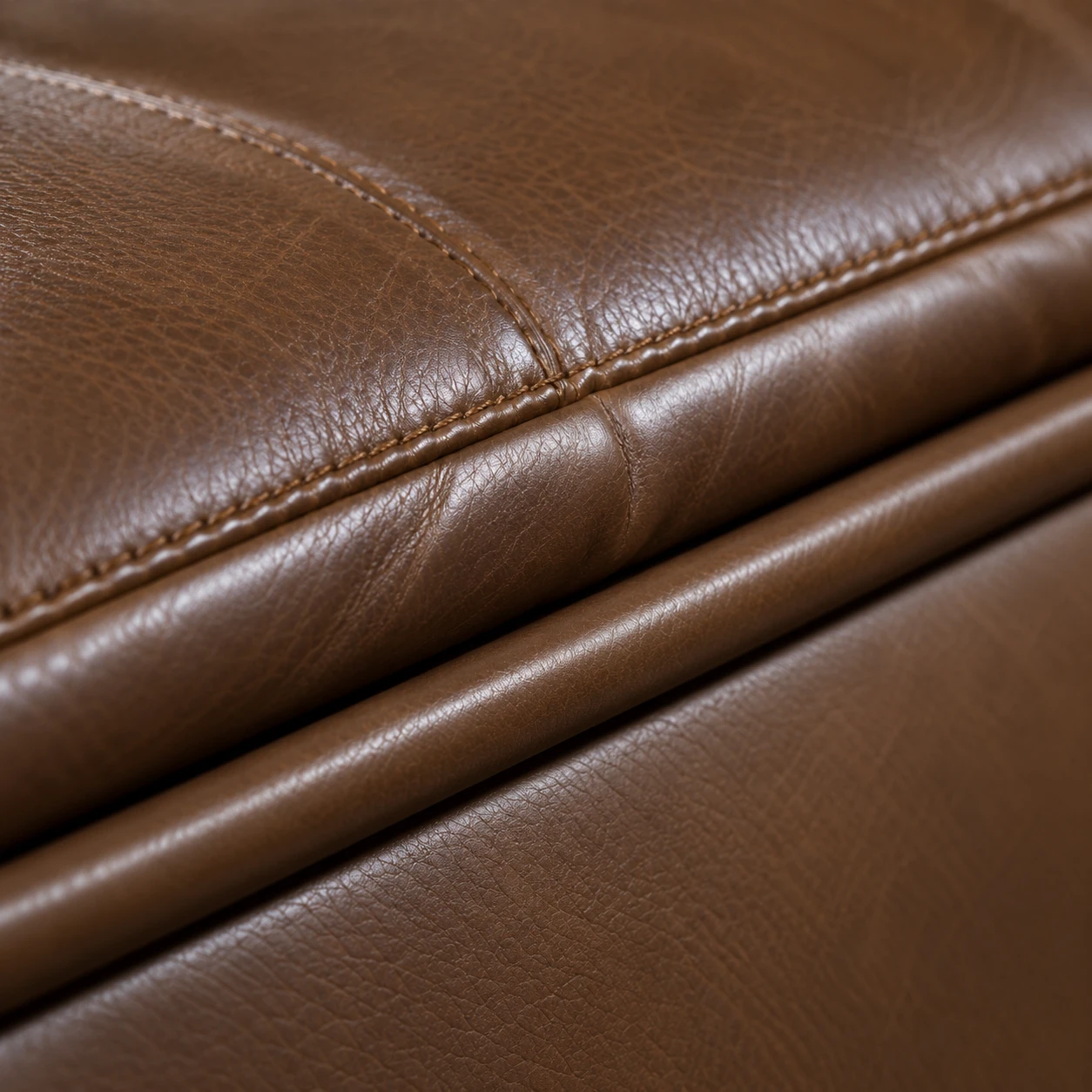 Close-up of brown leather cushion edges with piping cut from the same hide running between them