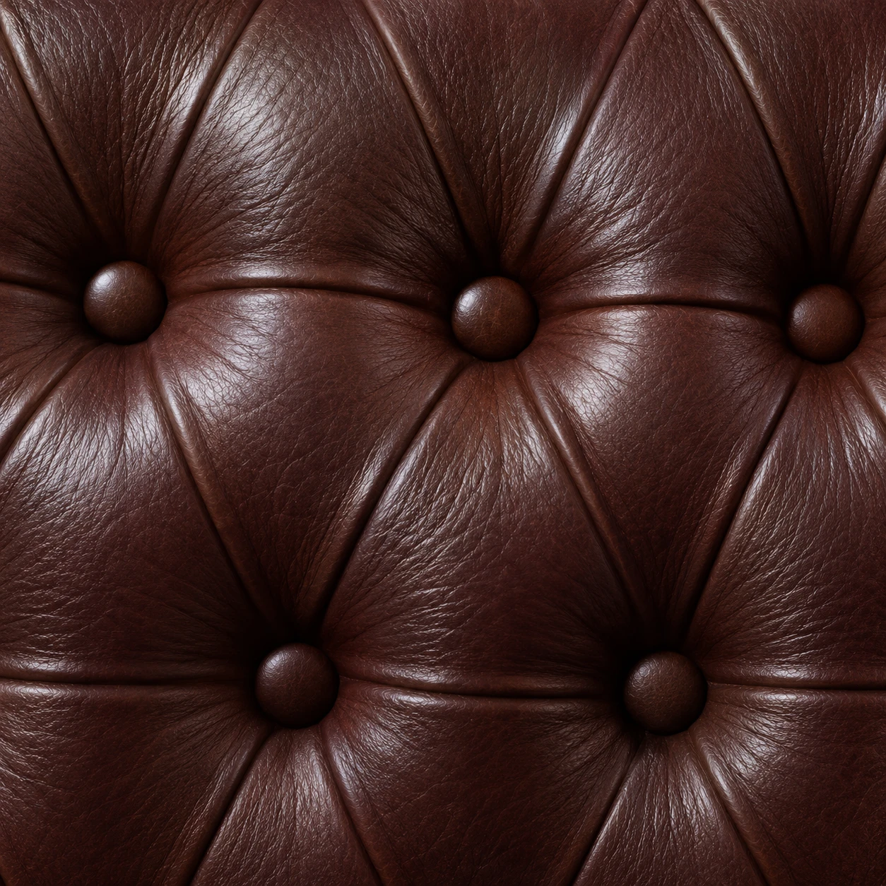 Close-up of deep buttoning in burgundy leather, with covered buttons pulled into diamond folds