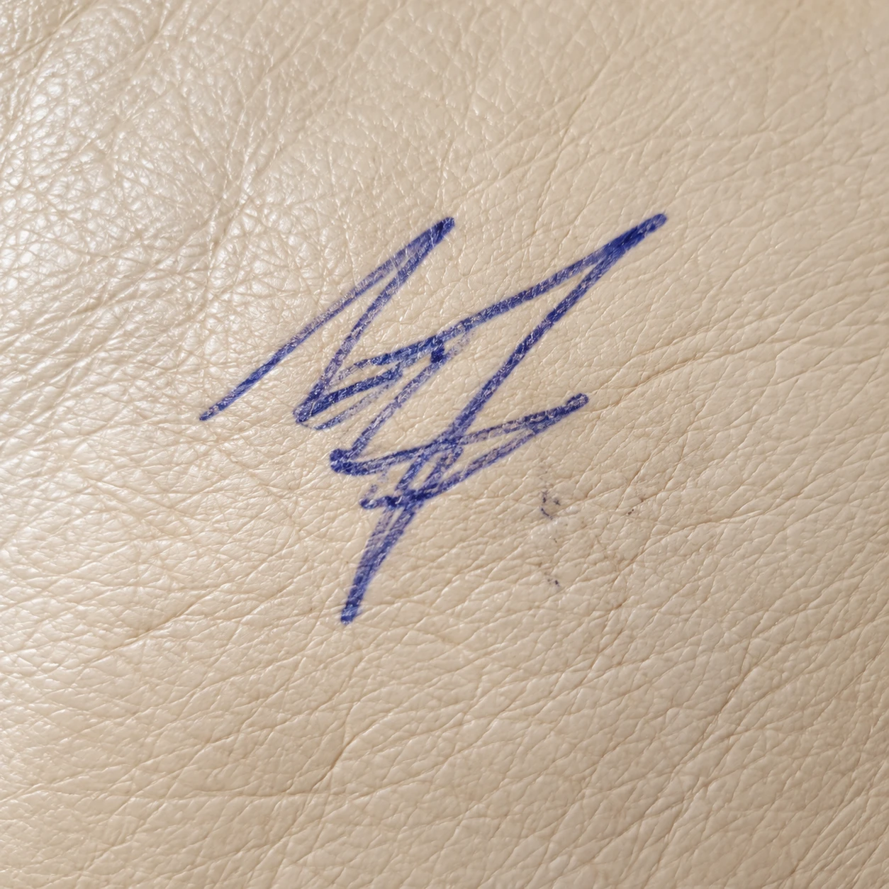 Blue ballpoint pen marks on a cream leather cushion
