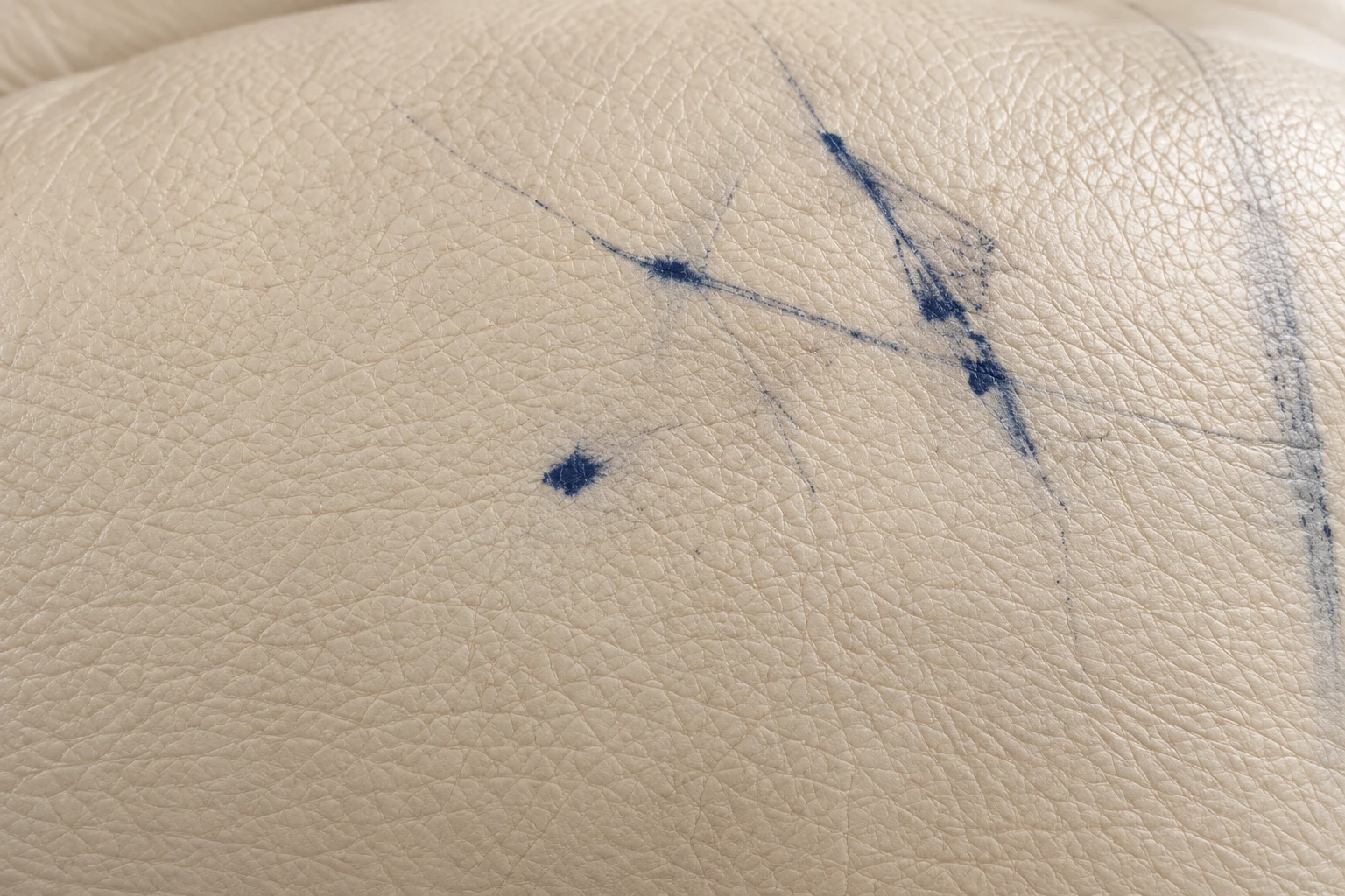 Blue ballpoint pen strokes drawn across cream leather