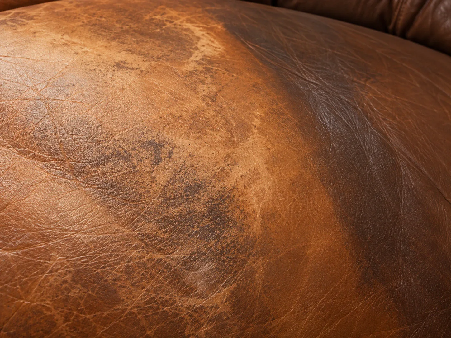 Tan leather sofa arm with a pale patch where the colour has worn away