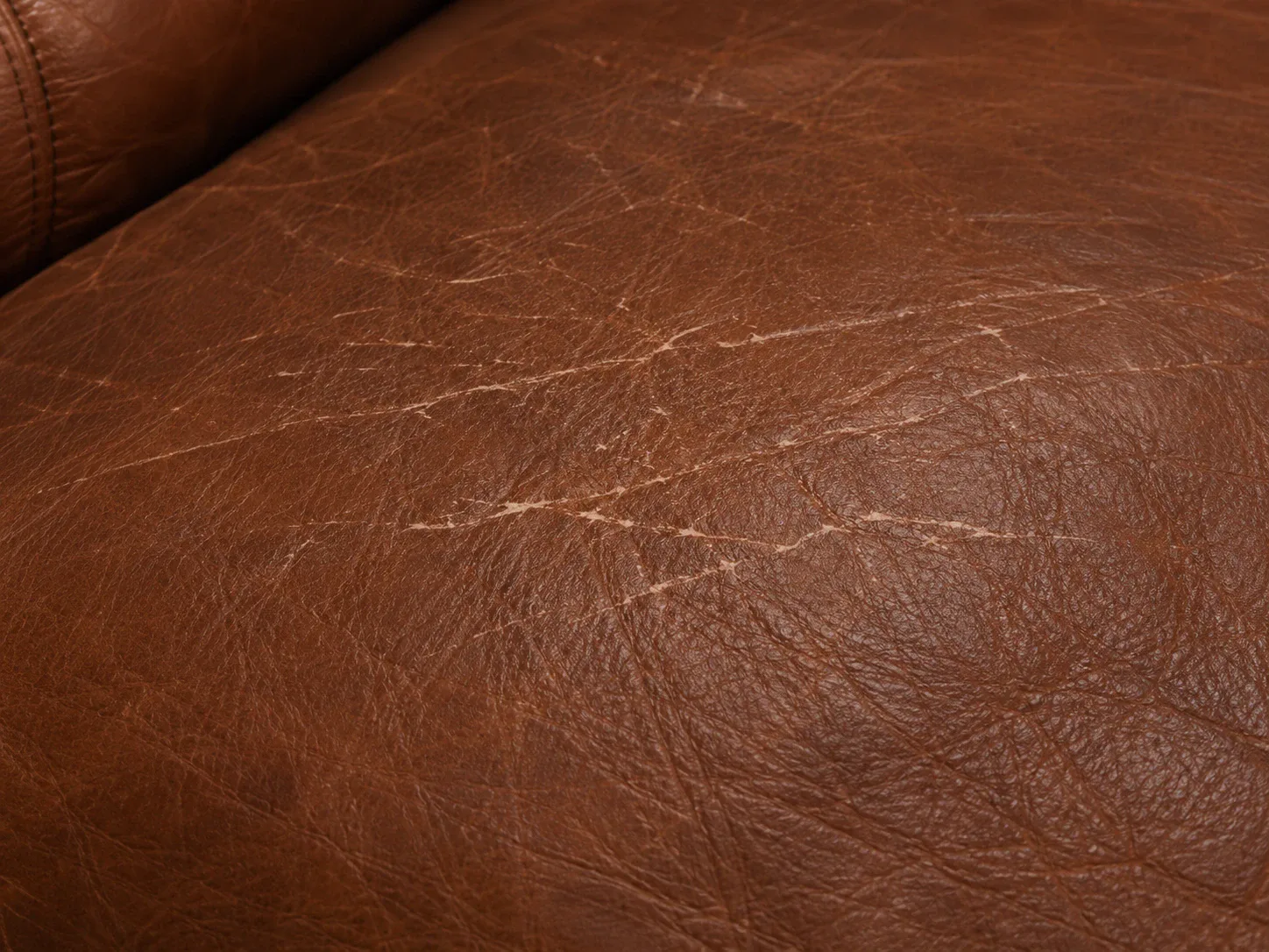 Pale scratch lines drawn across the finish of a brown leather seat cushion