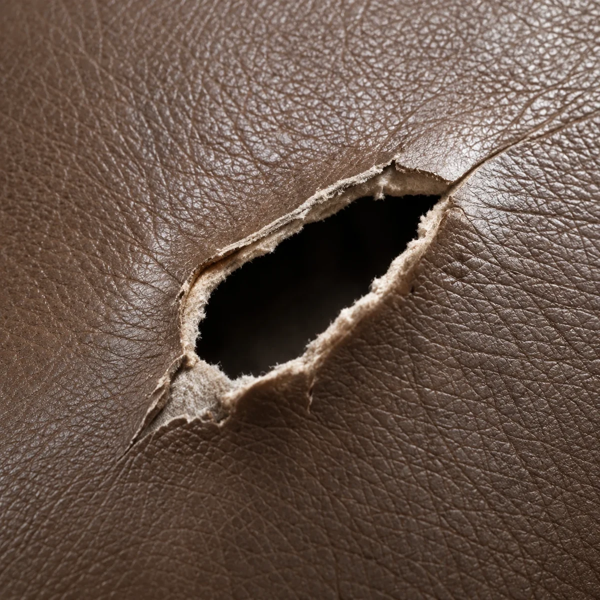 Open tear in brown leather