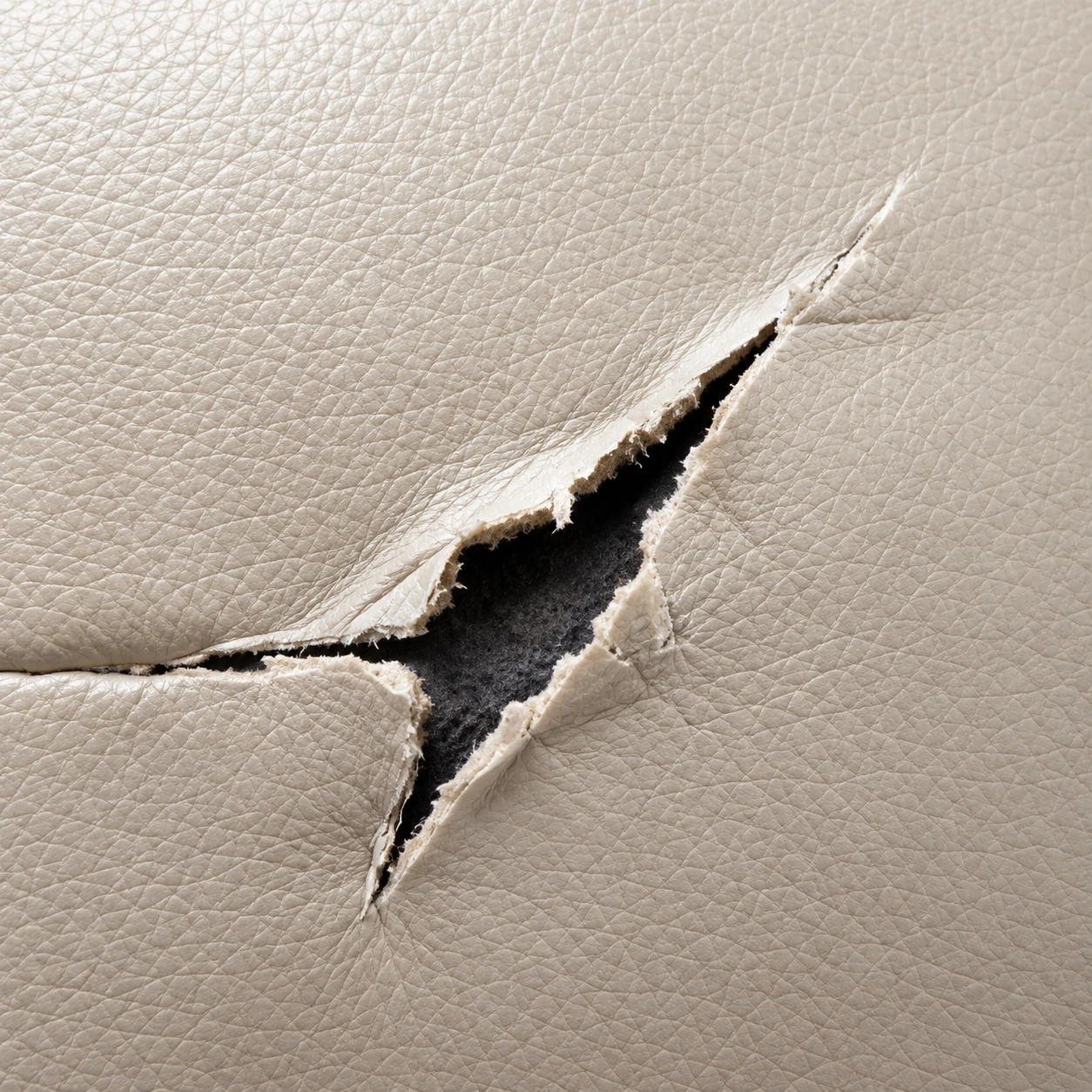 An open tear in cream leather with the edges lifted