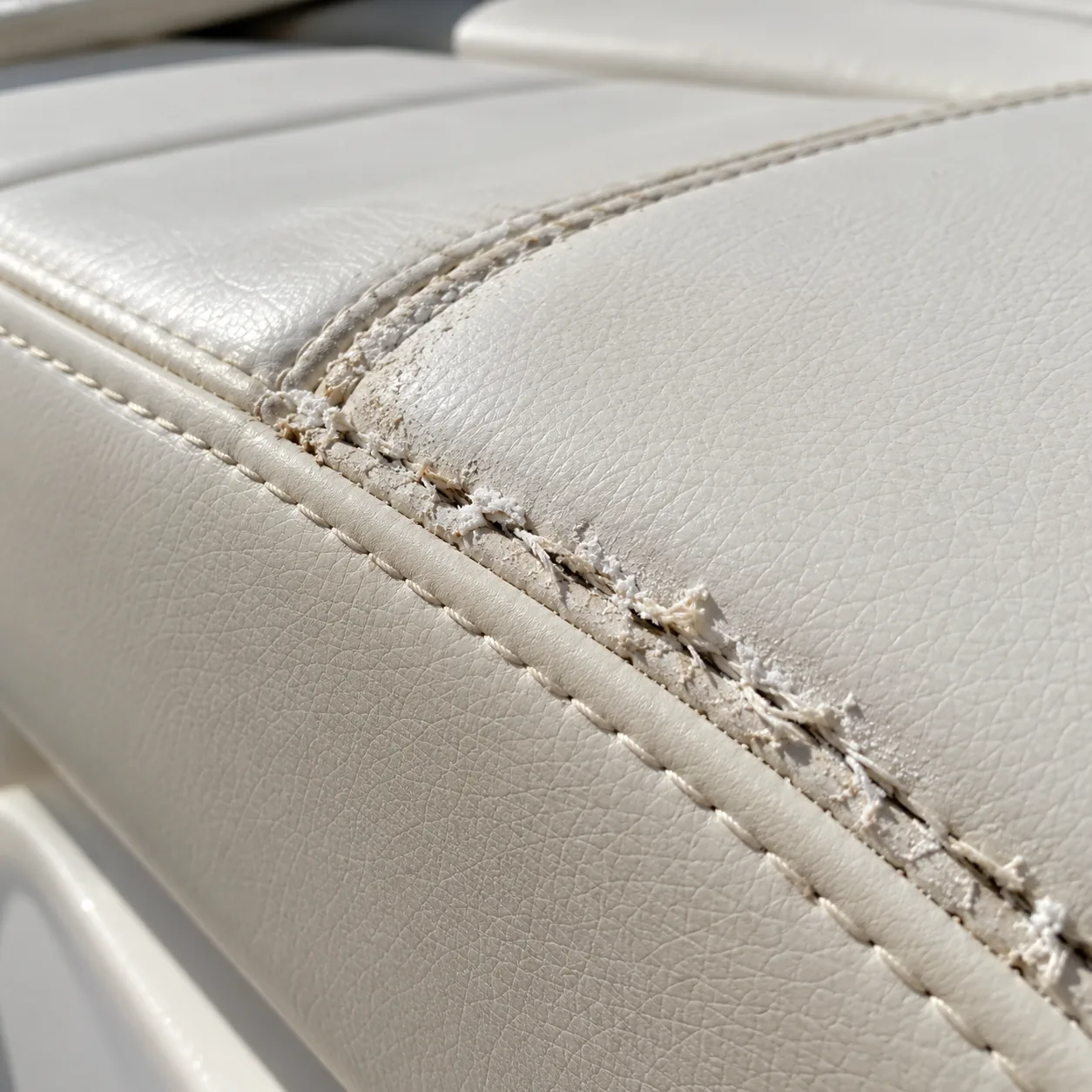 A chalky, powdered seam thread breaking while the vinyl beside it is sound