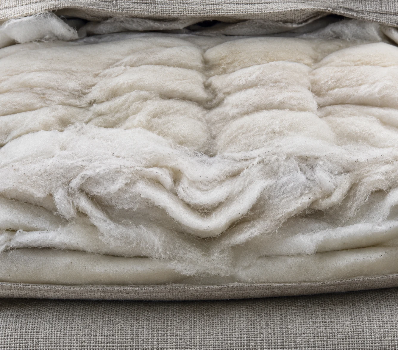 Matted and clumped polyester fibre wrap revealed inside an opened outdoor cushion cover