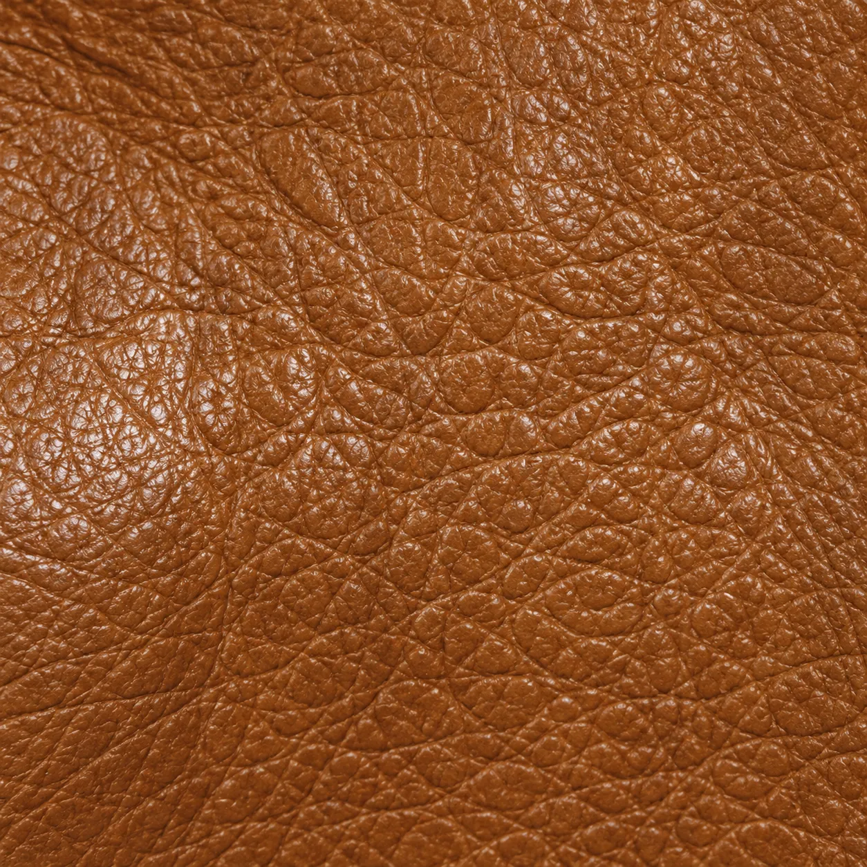 A close view of tan natural grain leather showing its open, uneven texture