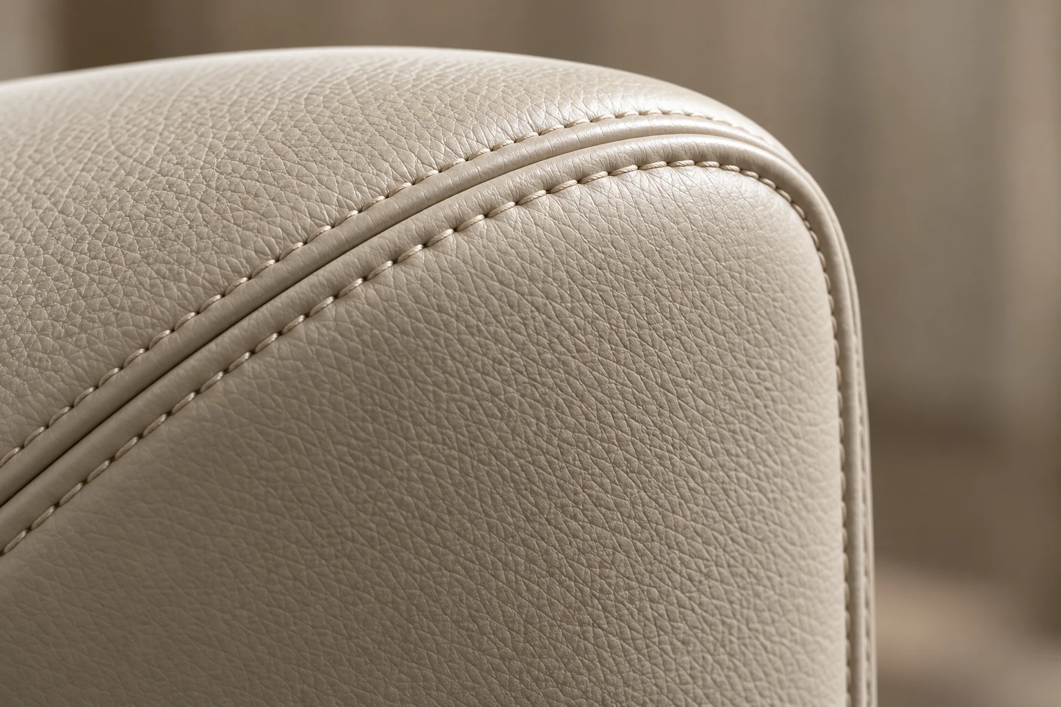 Twin rows of topstitching following the piped edge of a cream leather armrest