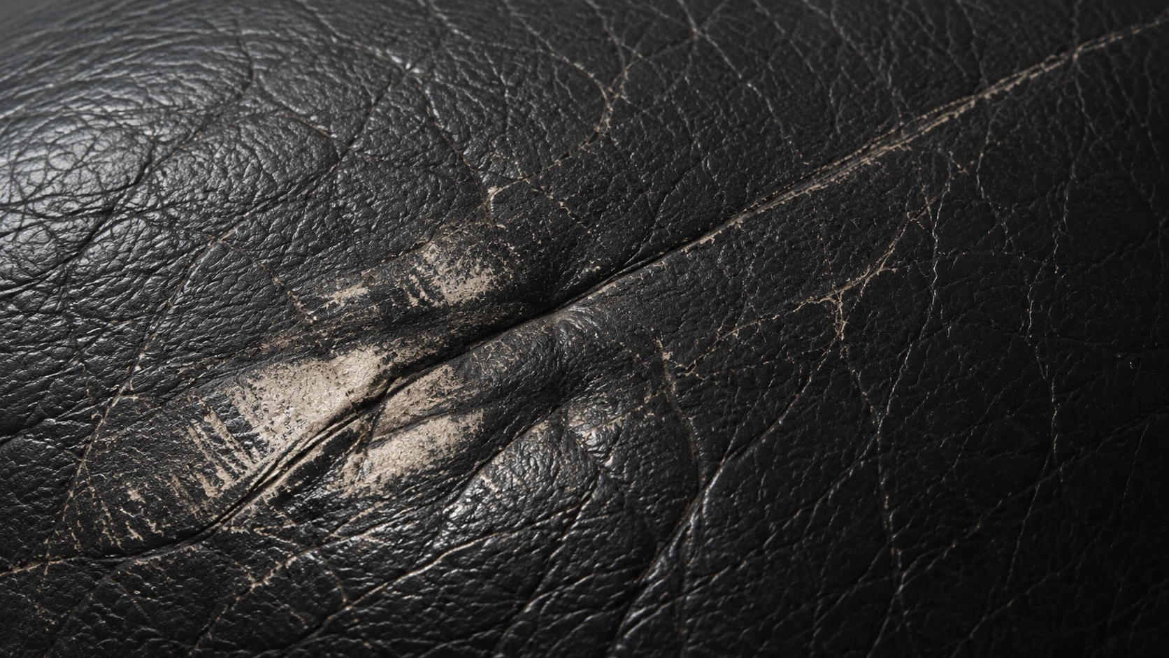 Abraded pale patches where the finish has been rubbed off black Natuzzi leather