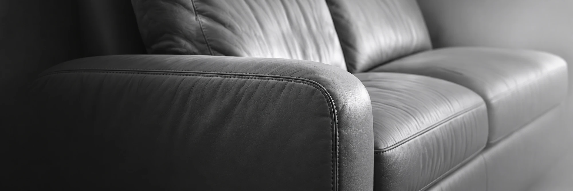 Close-up of the rolled arm and stitched seam of a leather sofa in black and white