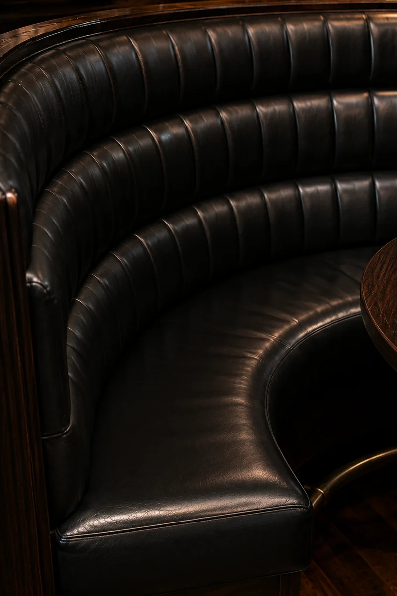 Curved channel-tufted club booth refinished in black