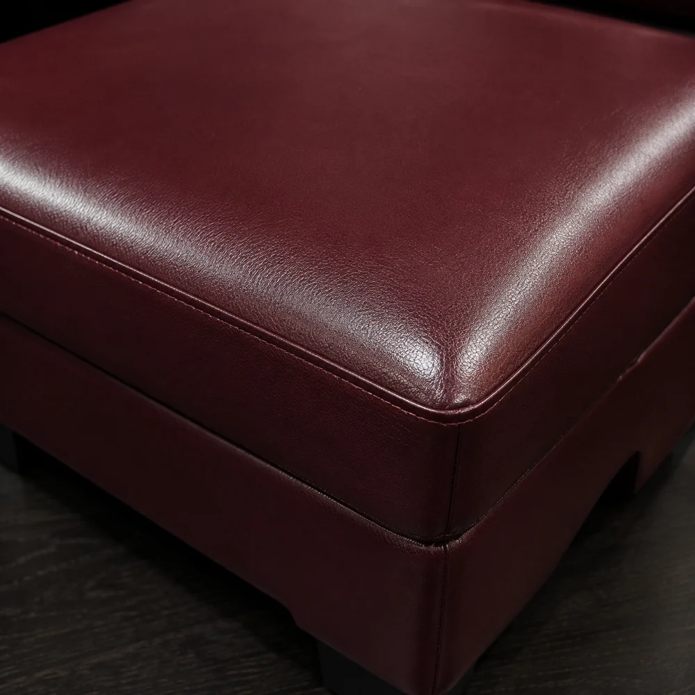 Corner of a burgundy pigmented leather ottoman showing a smooth sealed surface
