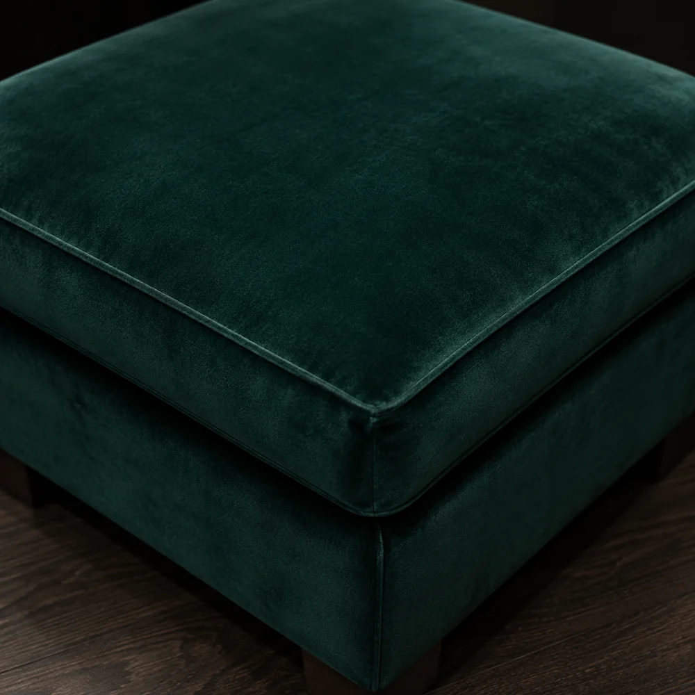 Corner of a deep green velvet ottoman showing the pile catching the light