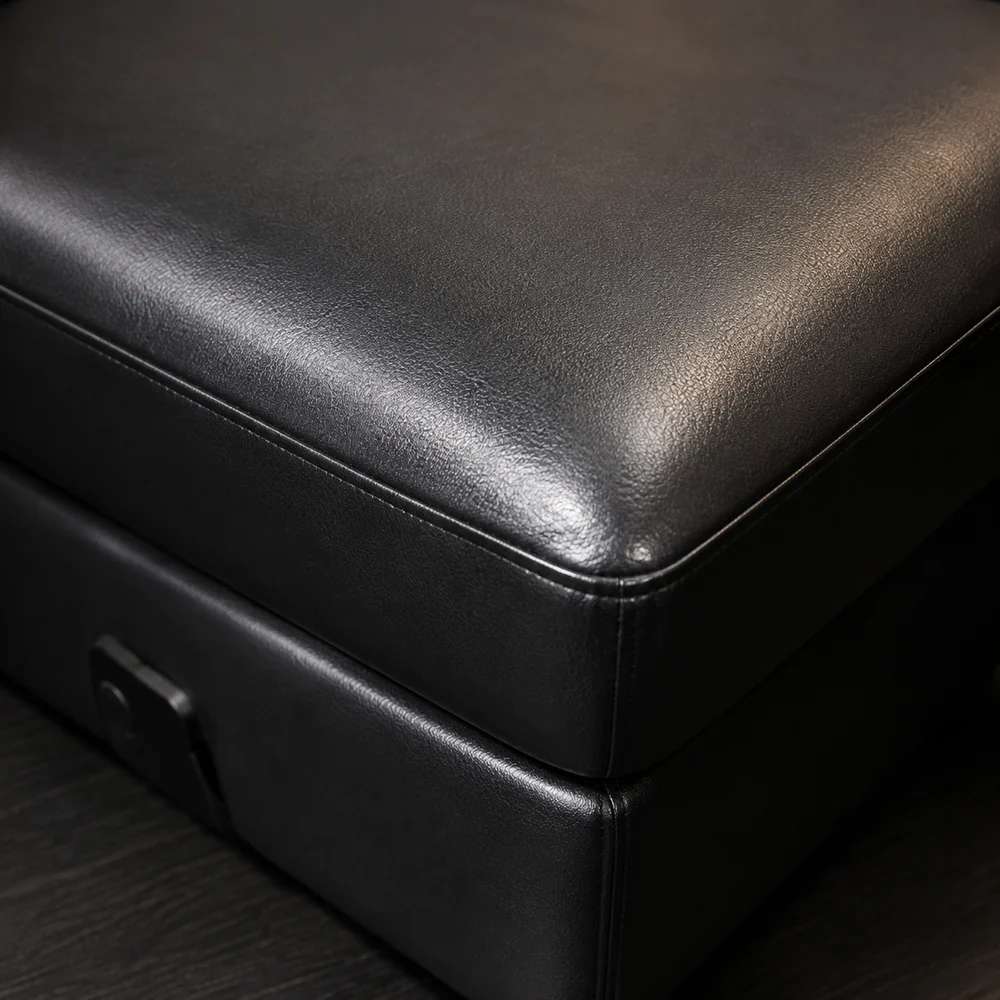 Corner of a black commercial vinyl ottoman with a welded seam and grained surface