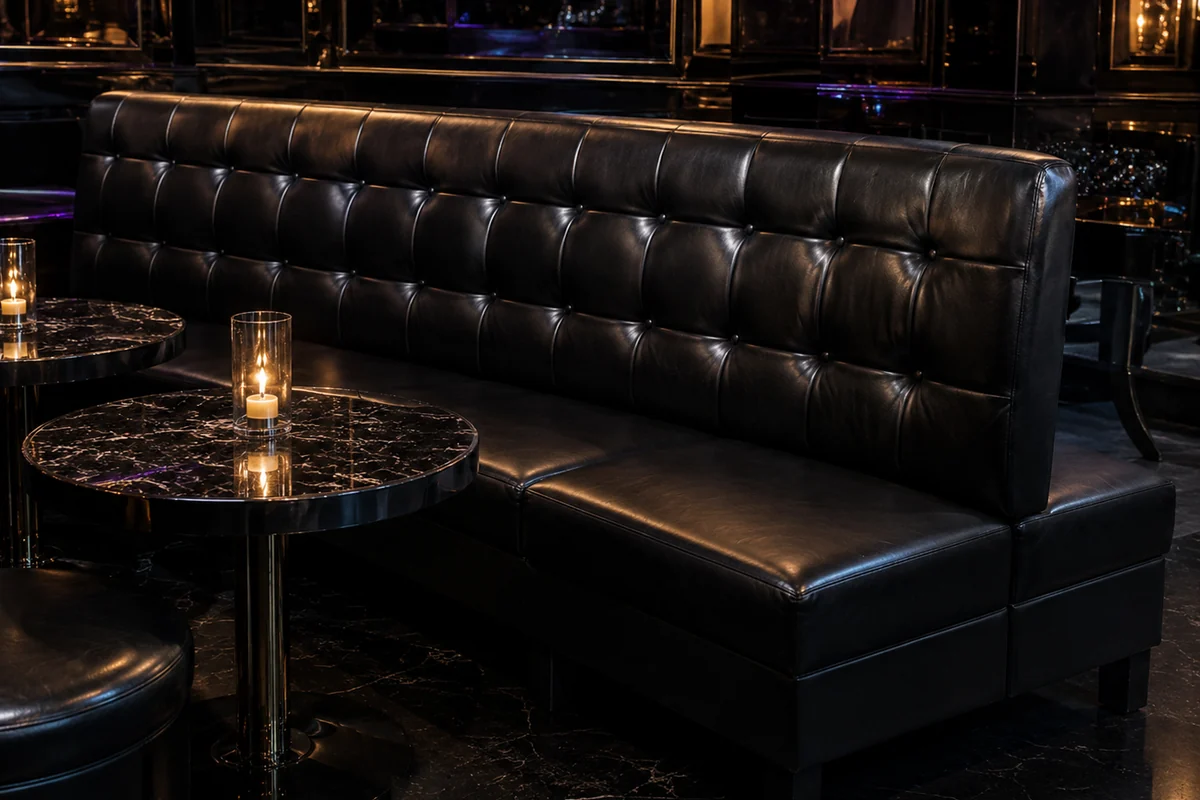 Long tufted banquette run along a nightclub wall with low tables in front