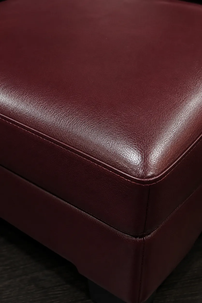 A burgundy faux leather upholstered ottoman corner