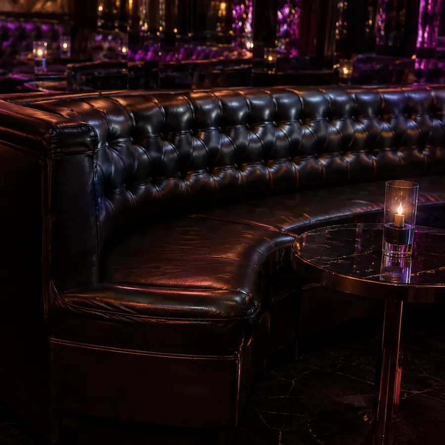 A curved tufted leather banquette under club lighting