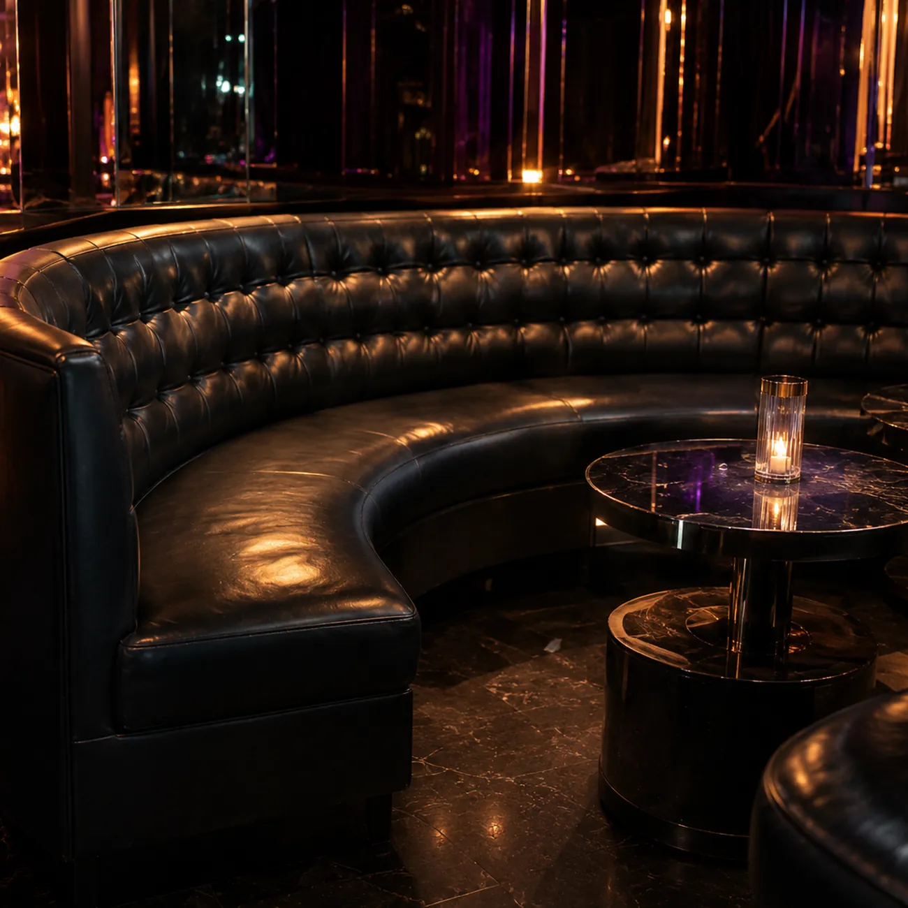 A curved black tufted VIP booth in a nightclub