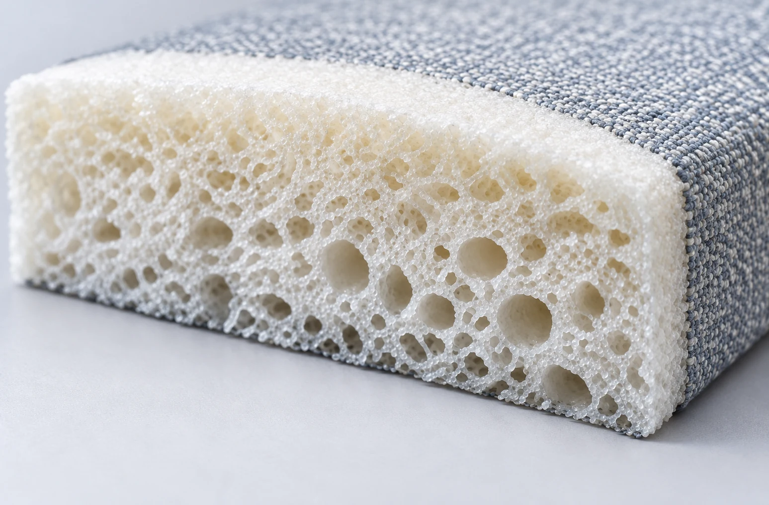 Cut-away of an outdoor cushion showing the open-cell drain foam core beneath the woven cover