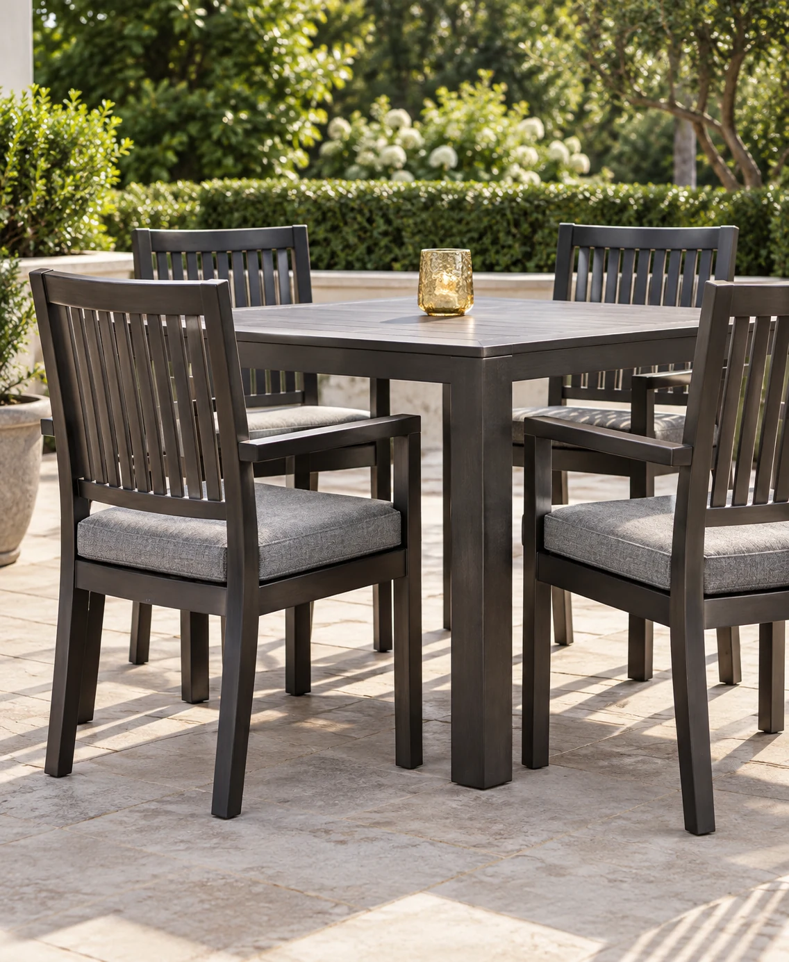 Outdoor dining chairs with grey seat pads around a stone table
