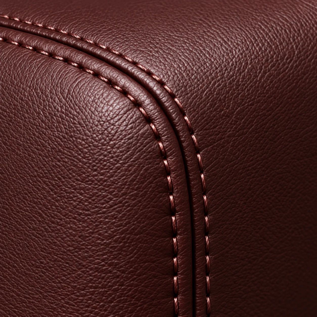 Macro view of a double stitched seam running through oxblood upholstery