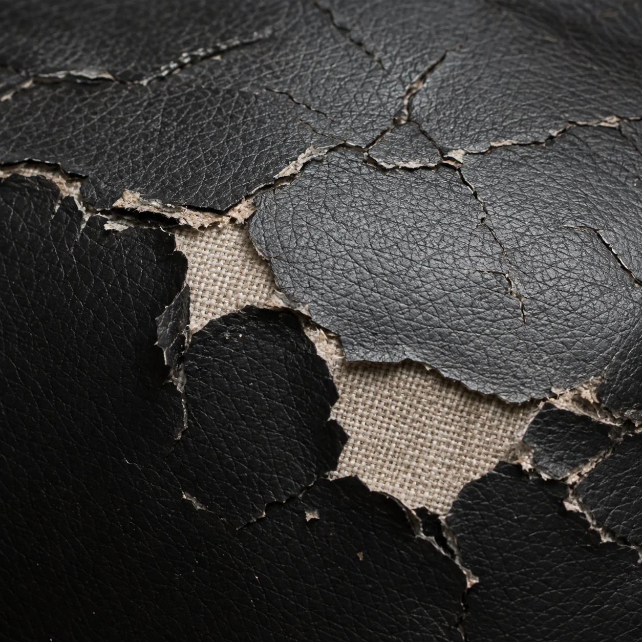 Home theater seat cover with the coating peeled away to expose the woven fabric backing underneath