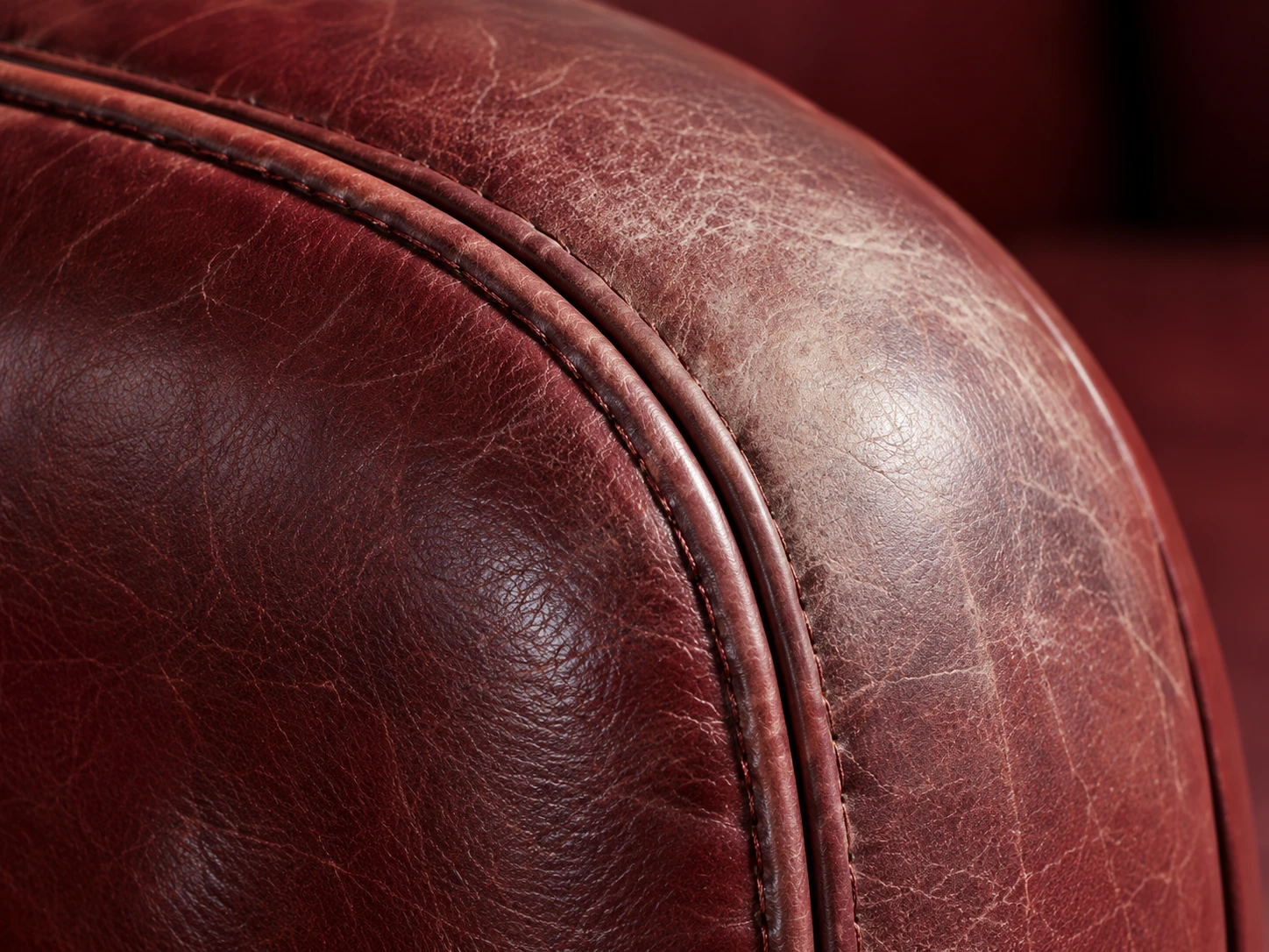 Faded patch on the rolled arm of an oxblood leather armchair