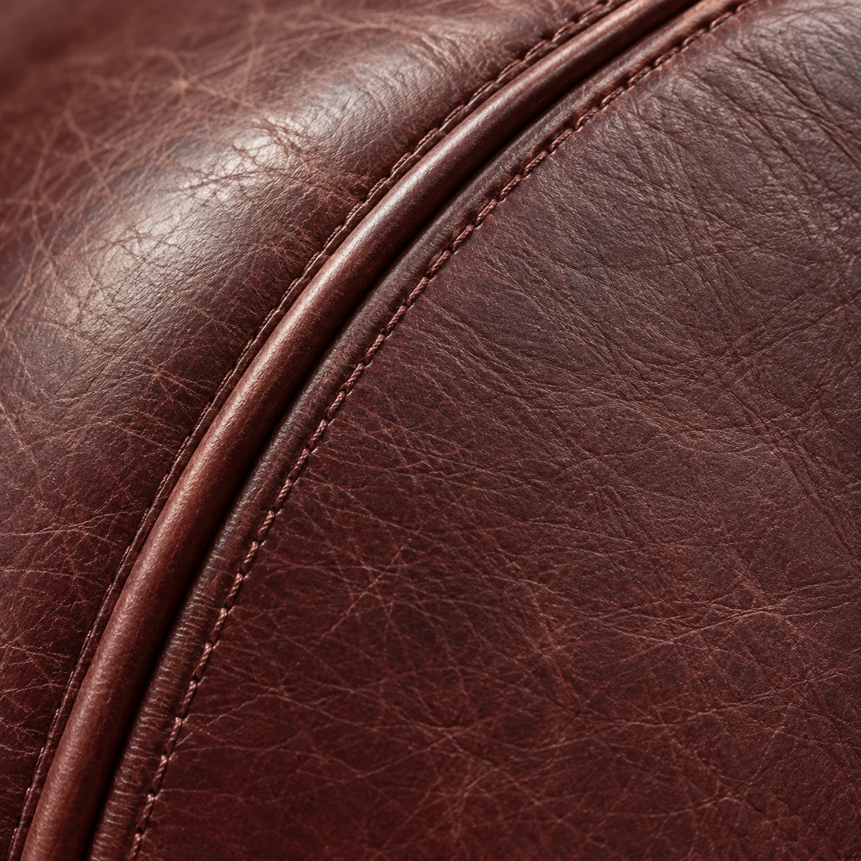 Curved piping seam on oxblood leather