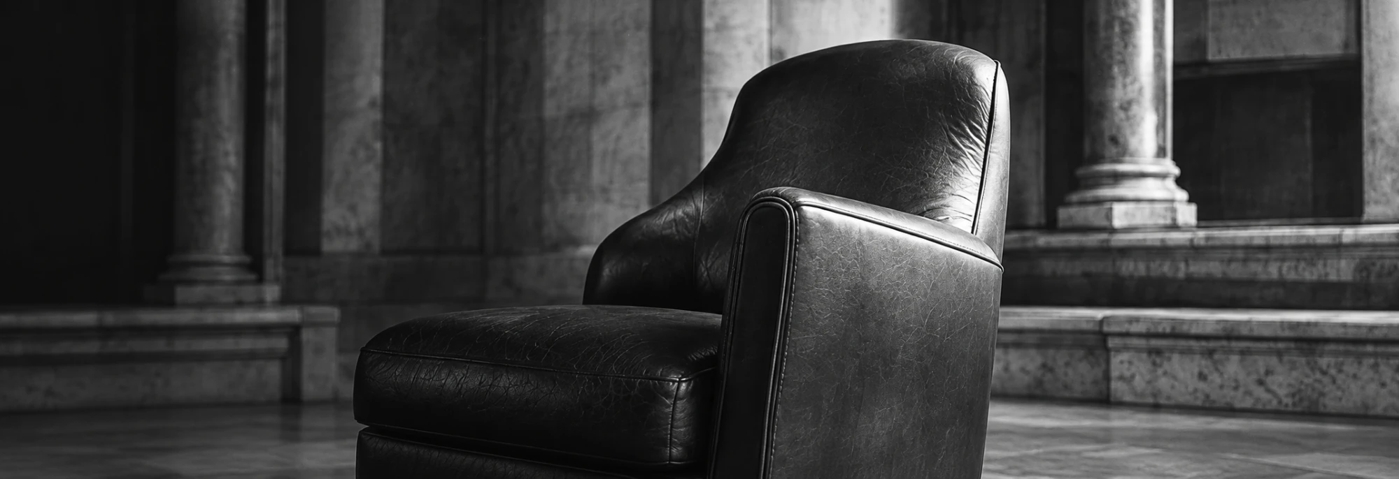 Dark leather armchair in a marble colonnade, black and white