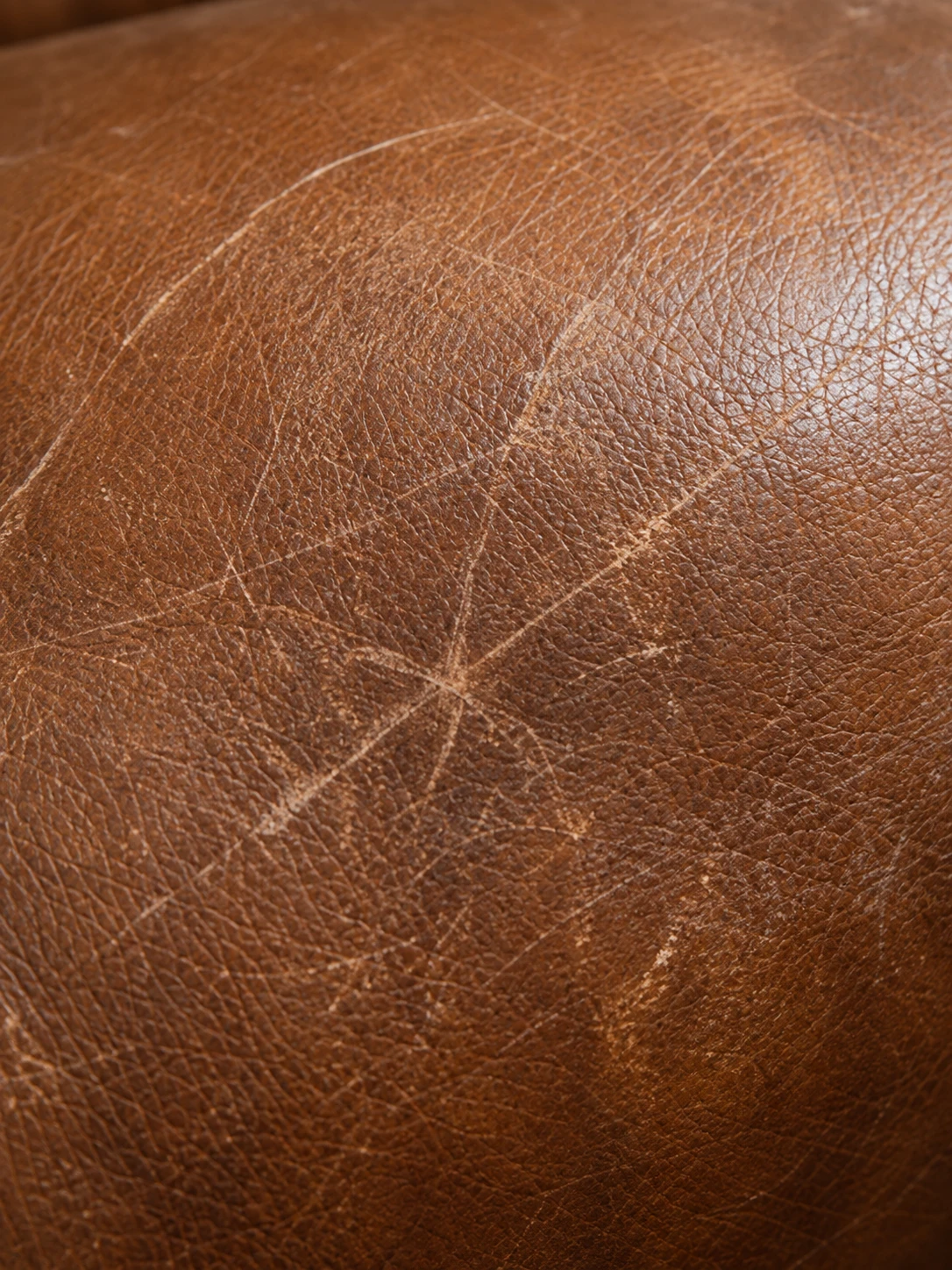Pale criss-cross scuffs across mid-brown leather