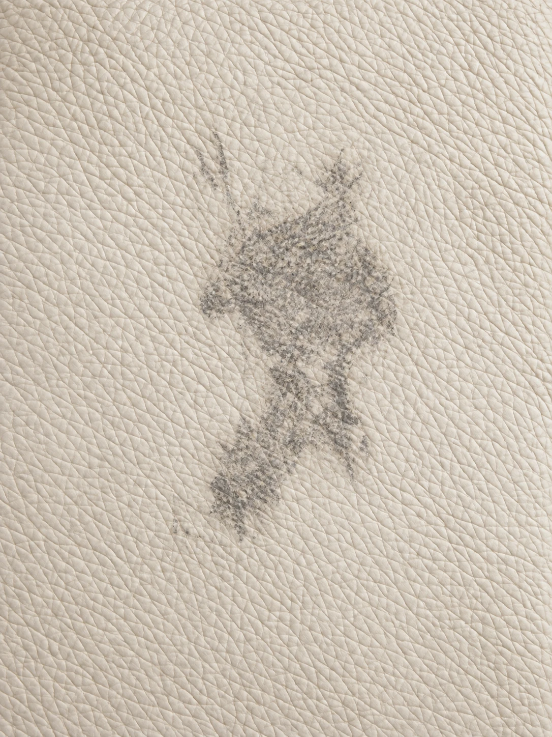 Dark grey transfer mark absorbed into cream leather