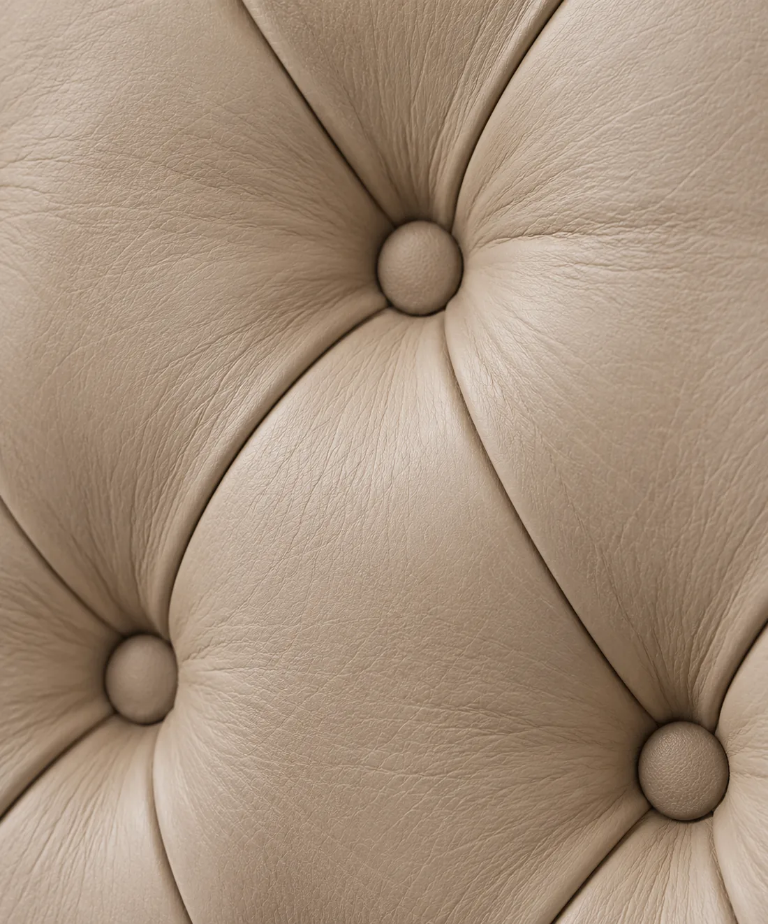 A close view of cream leather in a deep-buttoned diamond pattern with covered buttons at each point