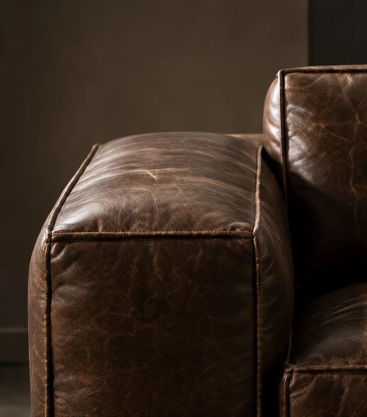 Corner of a dark brown leather sofa with loose cushions
