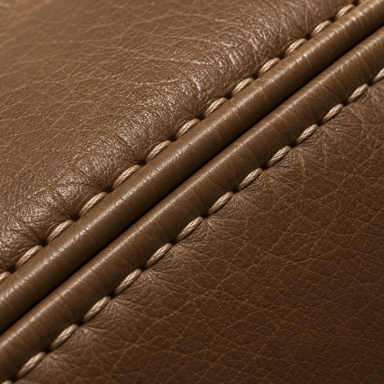 Close view of double contrast topstitching along a welted brown leather seam