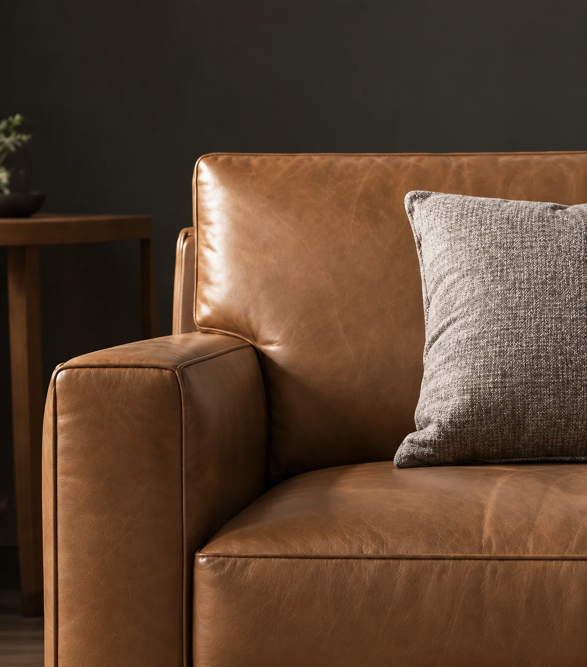 Tan leather sofa with a grey pillow