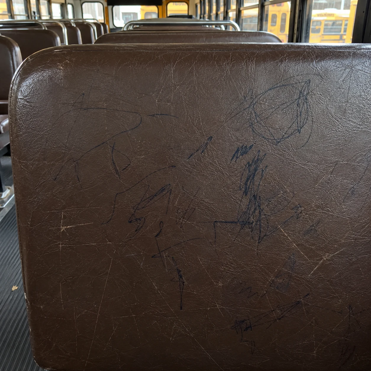 Ballpoint and marker marks on a school bus seat back