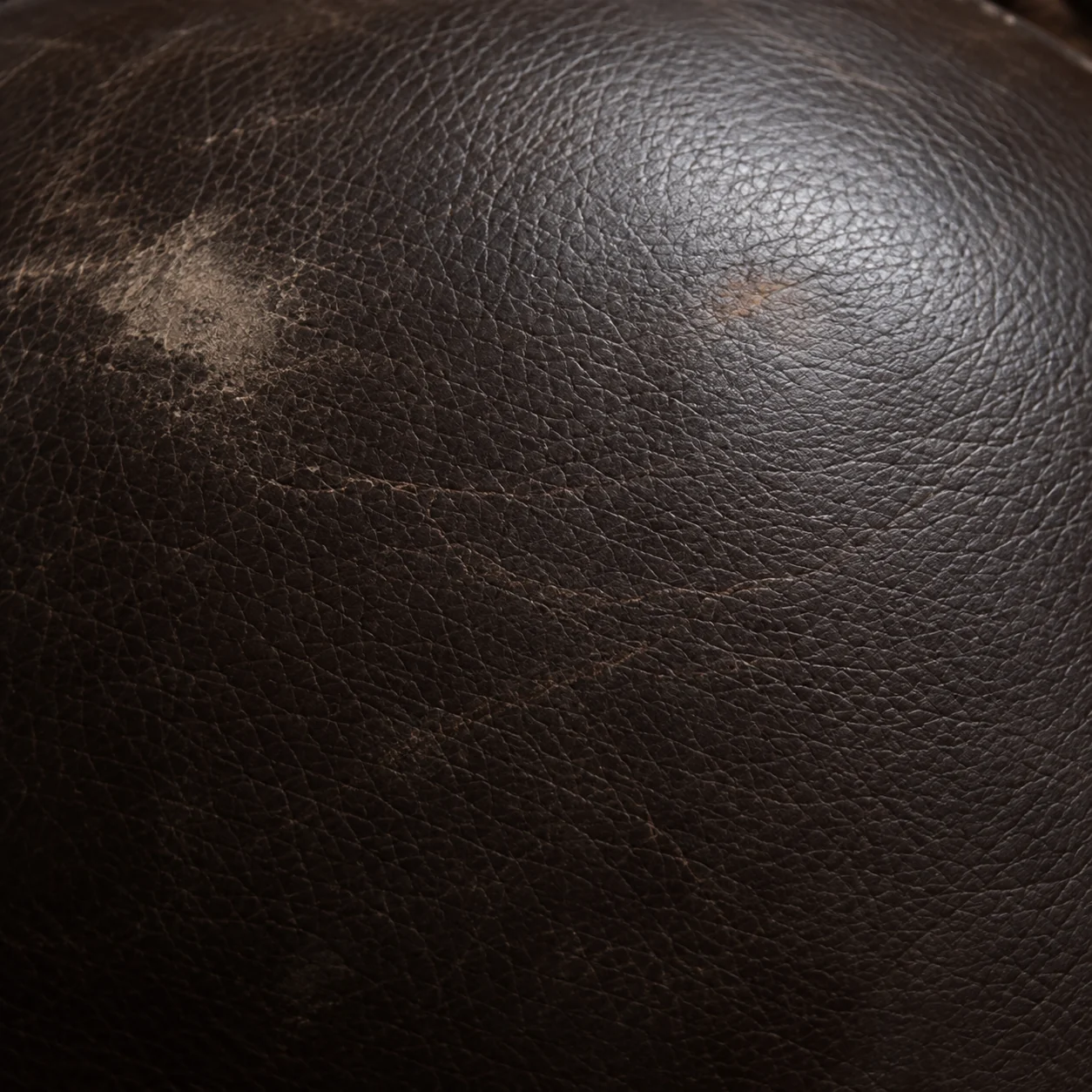 Pale abrasion scuffing over the stitched corner of a theater seat