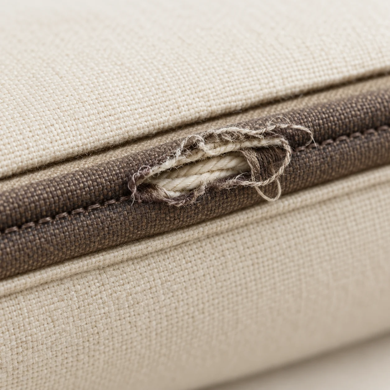 Split seam on a cushion cover with frayed thread along the boxing