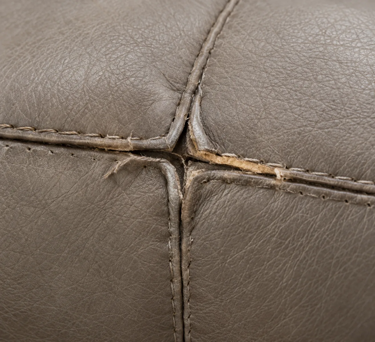 Grey bench leather opened along a stitched seam where two panels meet