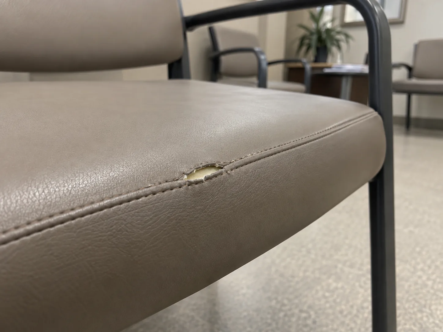 A split seam on the front edge of a waiting room chair seat