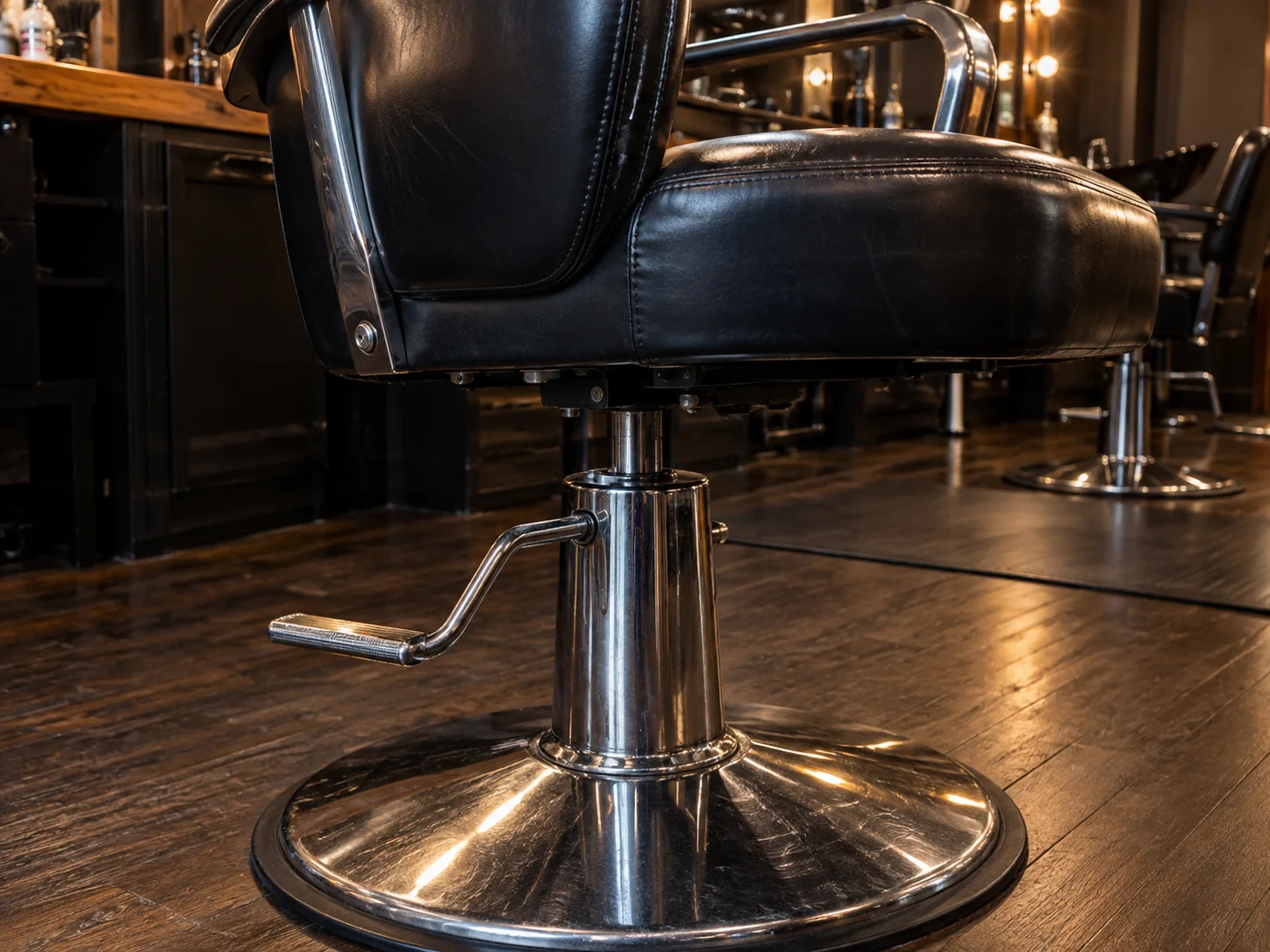 Close view of a black styling chair seat meeting its chrome hydraulic base