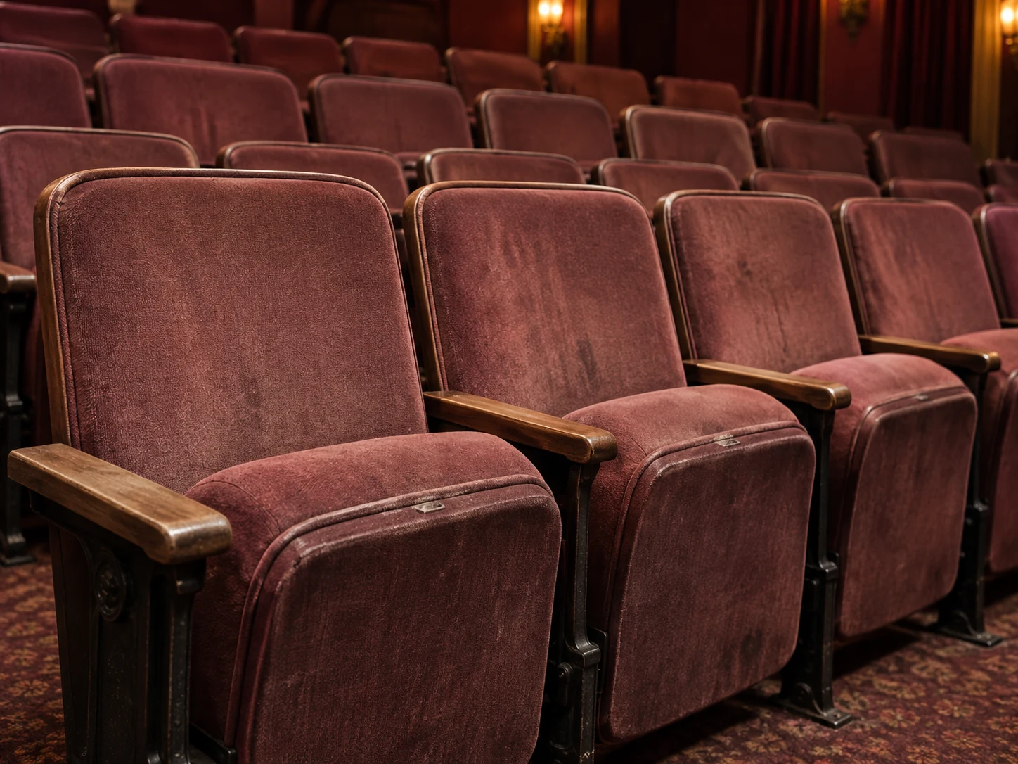 Faded red velvet theater seats before the work