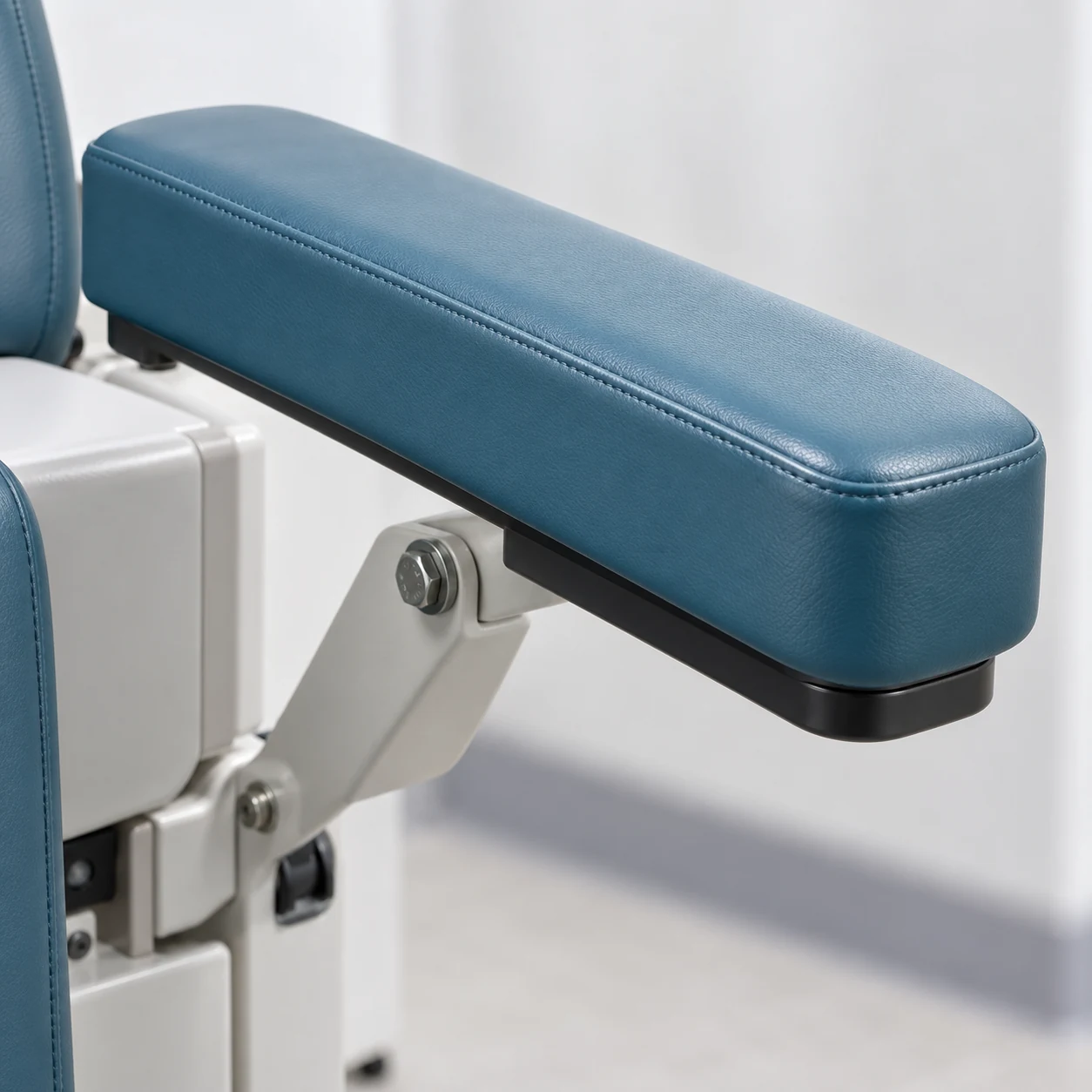 Treatment chair armrest pad bolted to the pivot bracket that carries it