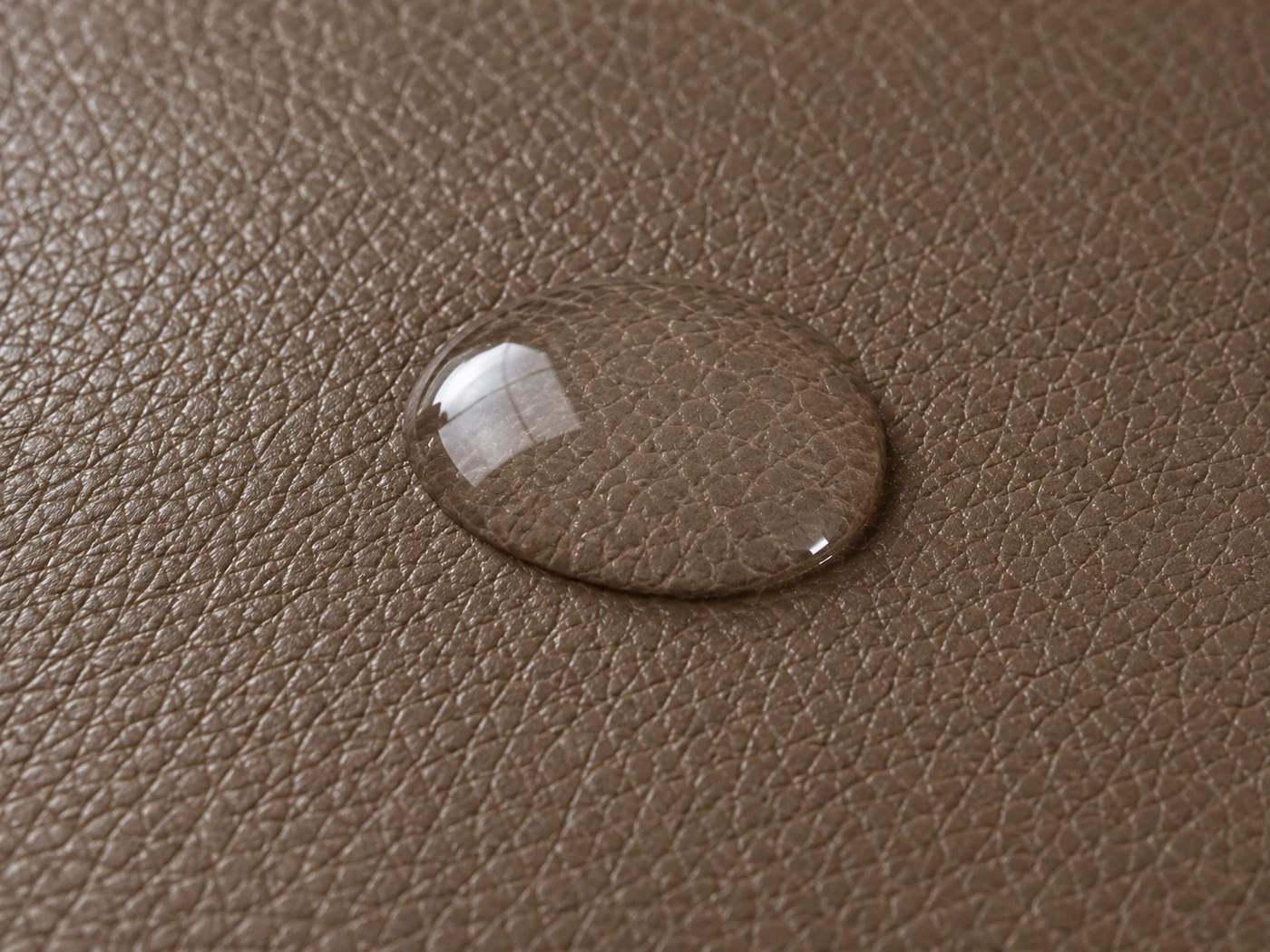 A bead of water sitting proud on taupe pigmented leather, with no darkening around it