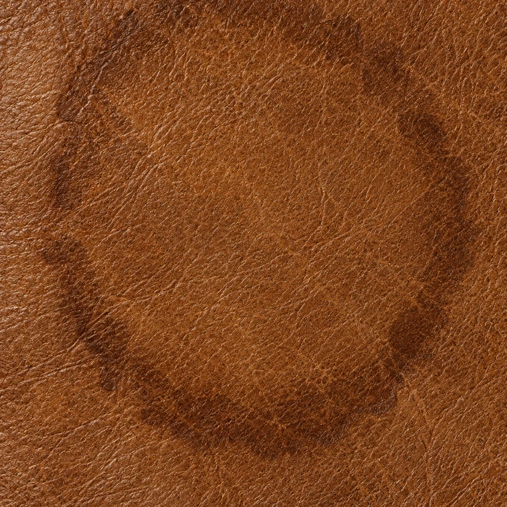 Brown leather with a finished water ring: a dark loaded rim around a lighter dried centre