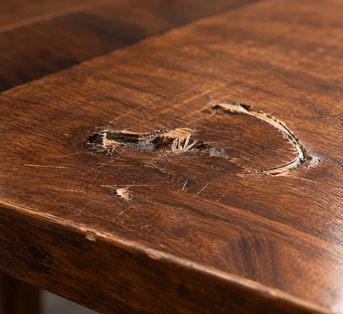 Deep gouge torn out of a wooden table top