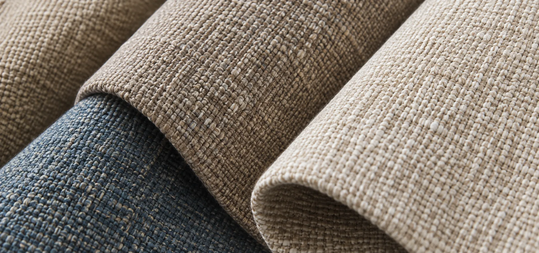 Woven upholstery fabric swatch rolls in blue, taupe and natural